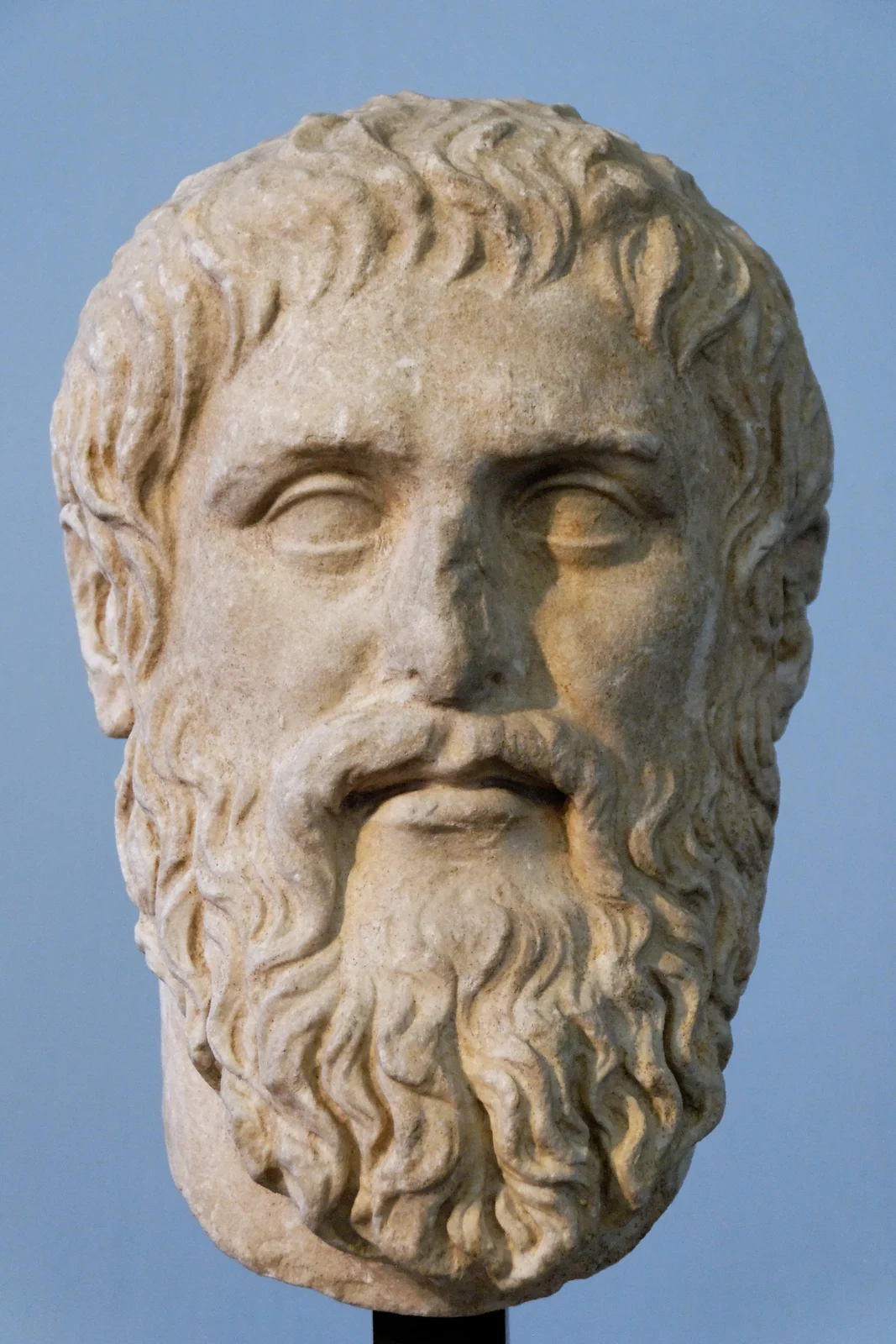 A marble portrait bust of a bearded man with a calm expression, in a museum.