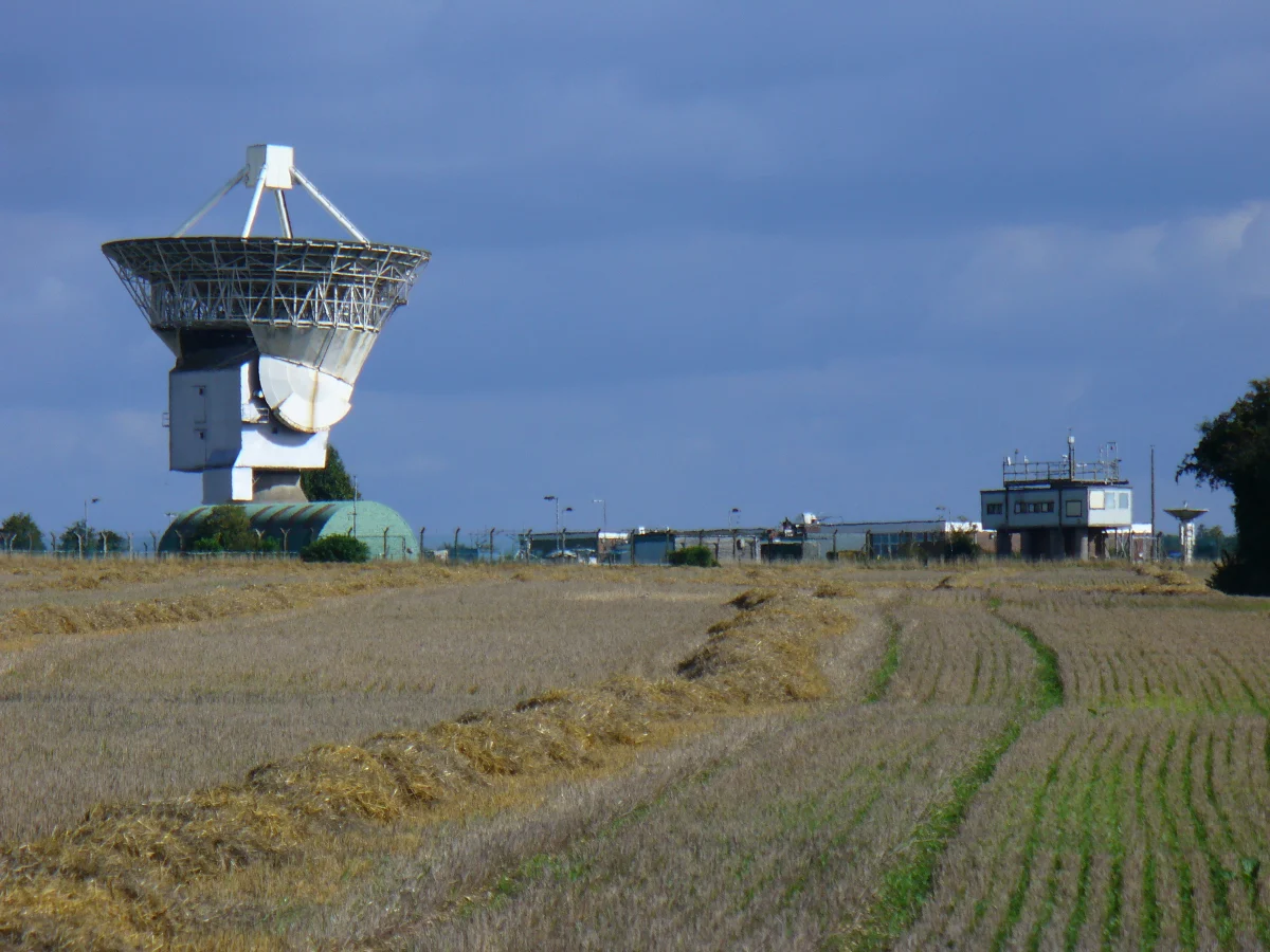 The Chilbolton radio dish and the observatory buildings seen across a stubble field in late summer.