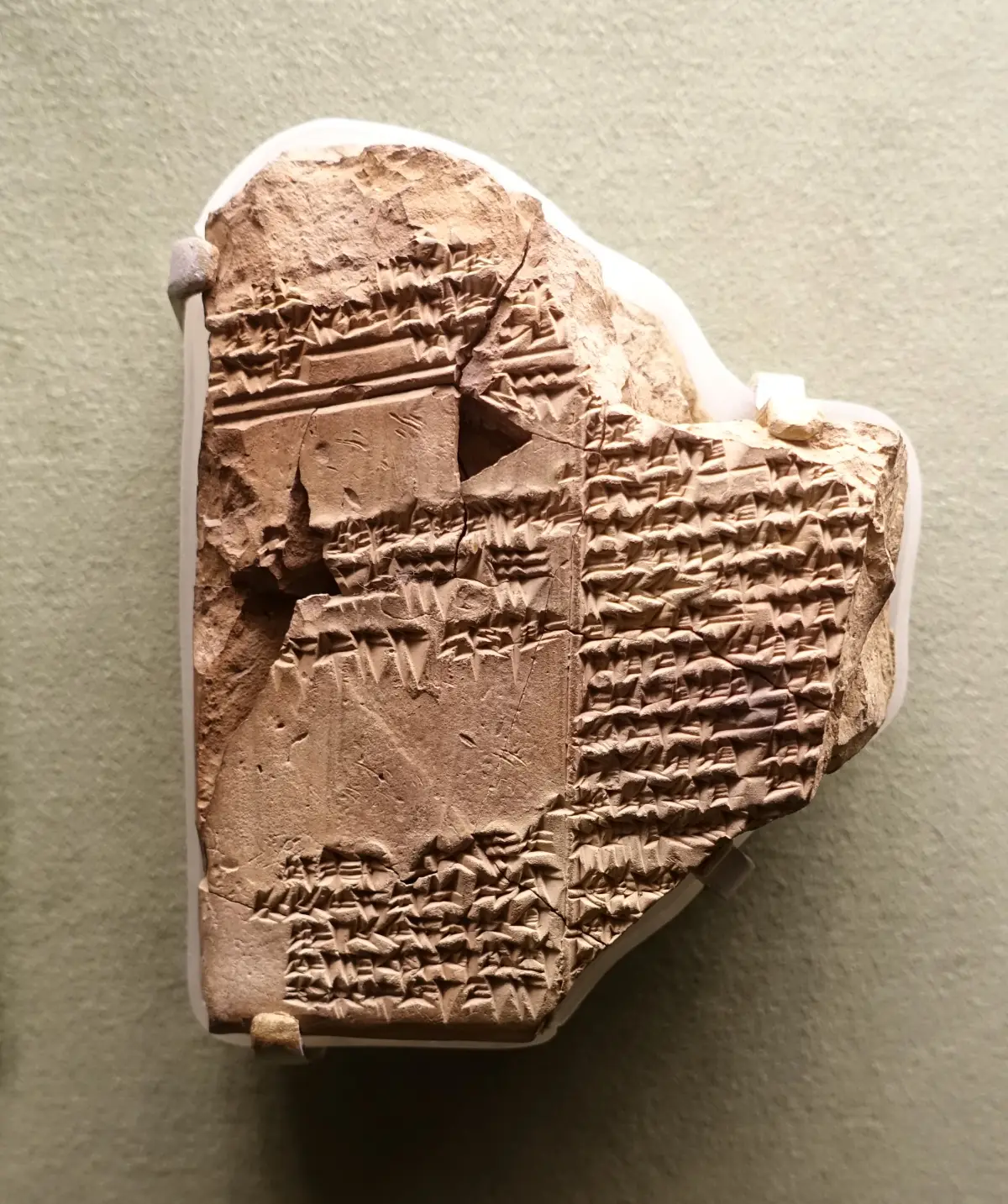 A small fragment of a clay tablet with closely written cuneiform signs, displayed against a pale background.