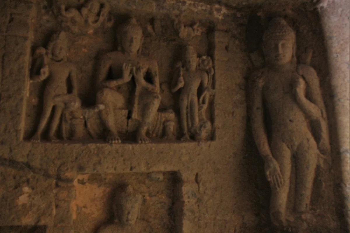 Figures cut in relief into a dark rock wall.