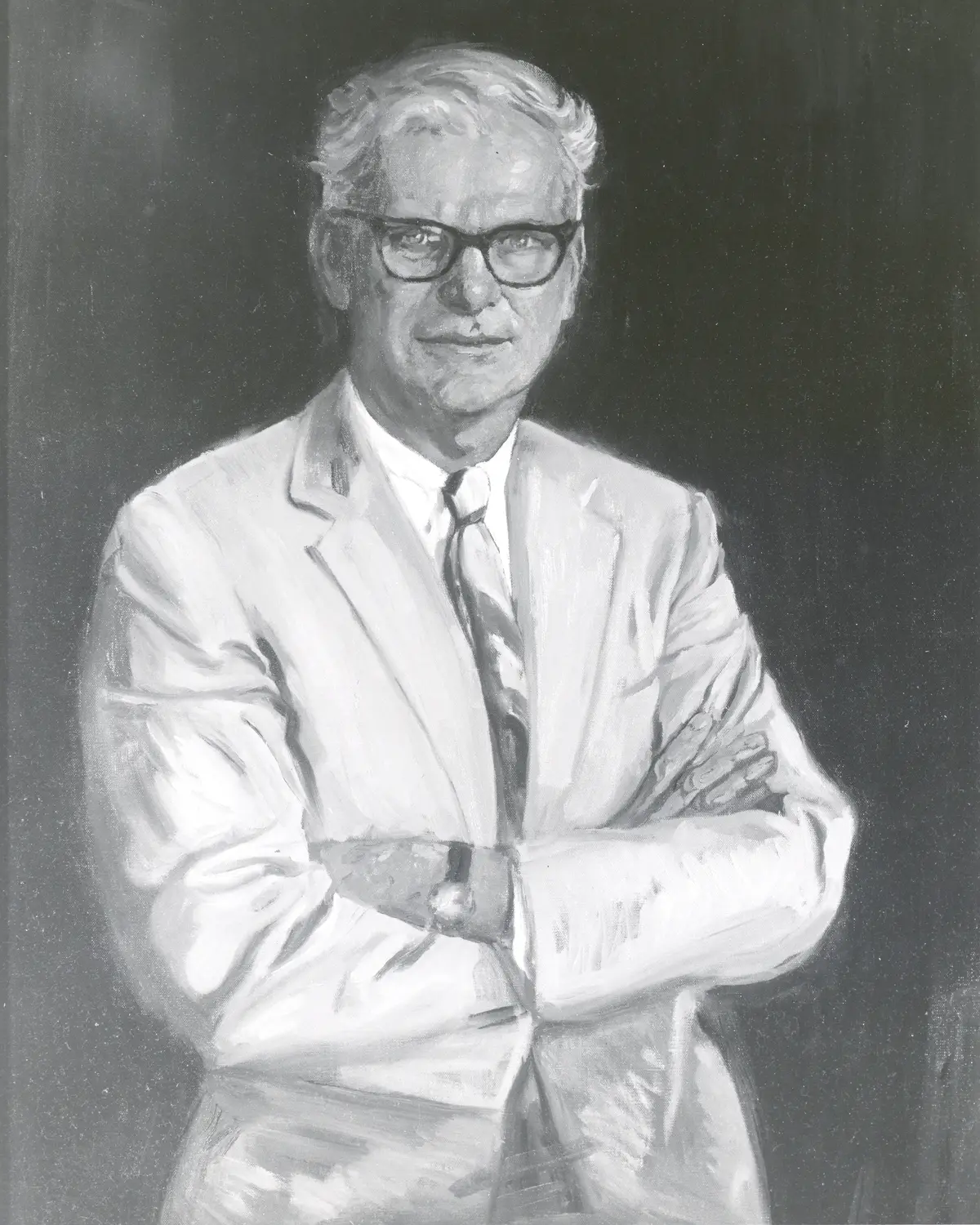 Black-and-white portrait of a man in glasses, suit and tie, arms folded.
