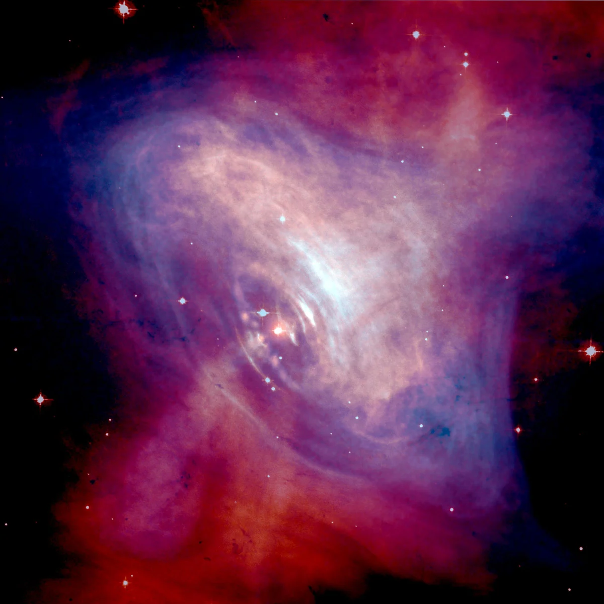 A glowing cloud of red and purple filaments with a bright blue-white centre, against black space with a few stars.