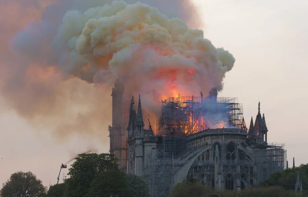 Flames and a yellow column of smoke rising from the roof of the cathedral.