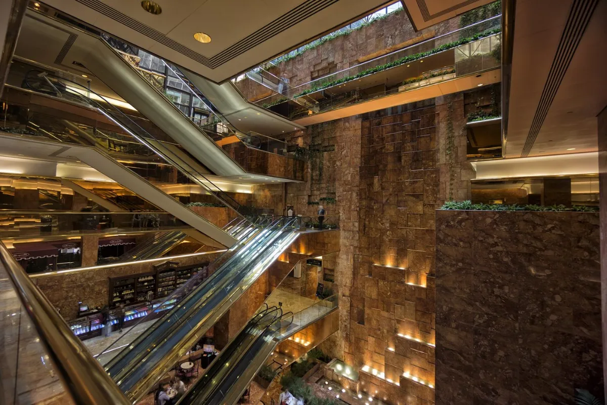Brass escalators crossing a marble atrium, seen from above.