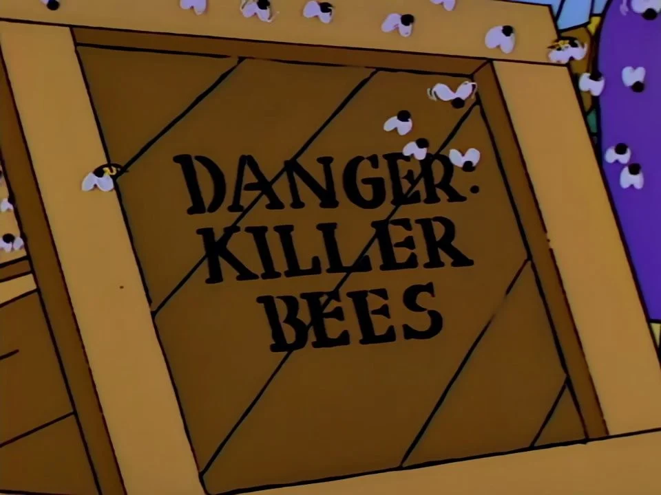 A broken wooden crate marked Danger: Killer Bees by an overturned truck, bees crawling out.
