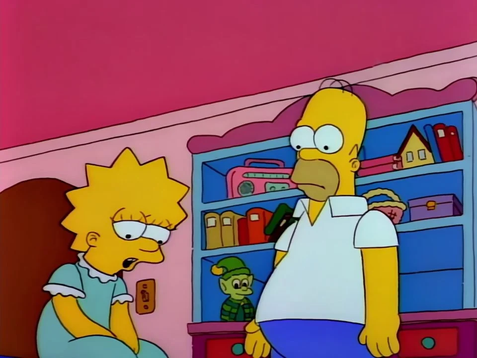 Lisa in a nightdress speaking, seated, while Homer stands by her bookshelf.