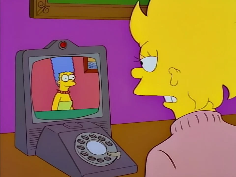 Adult Lisa facing a desk phone with a rotary dial and a small screen showing Marge.