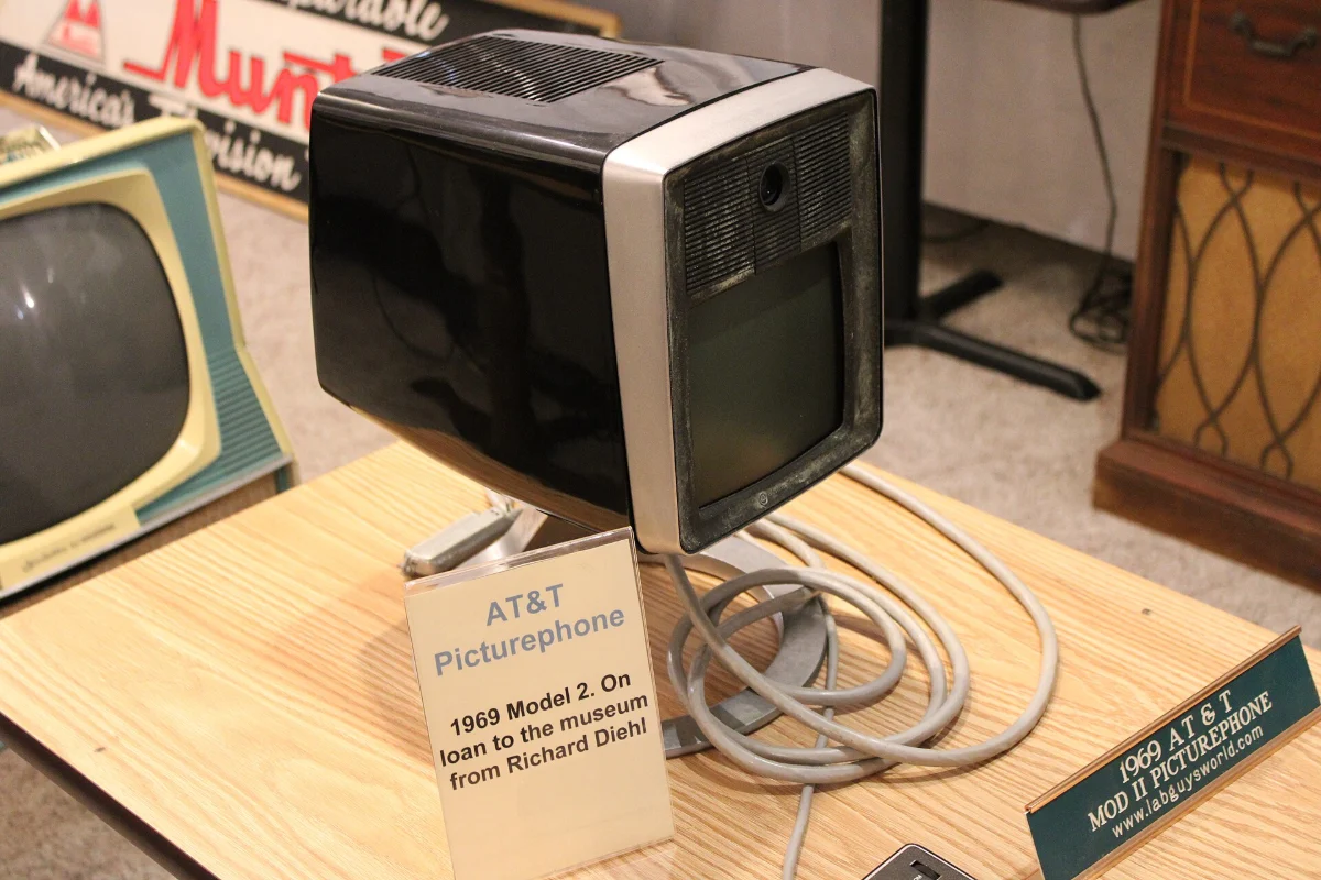 A boxy desk video telephone with a small screen, on display in a museum.