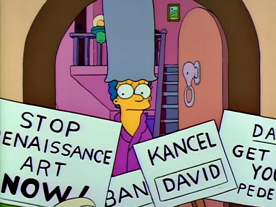 Marge in her bathrobe looking out of her door at protest placards reading Kancel David and Stop Renaissance Art Now.