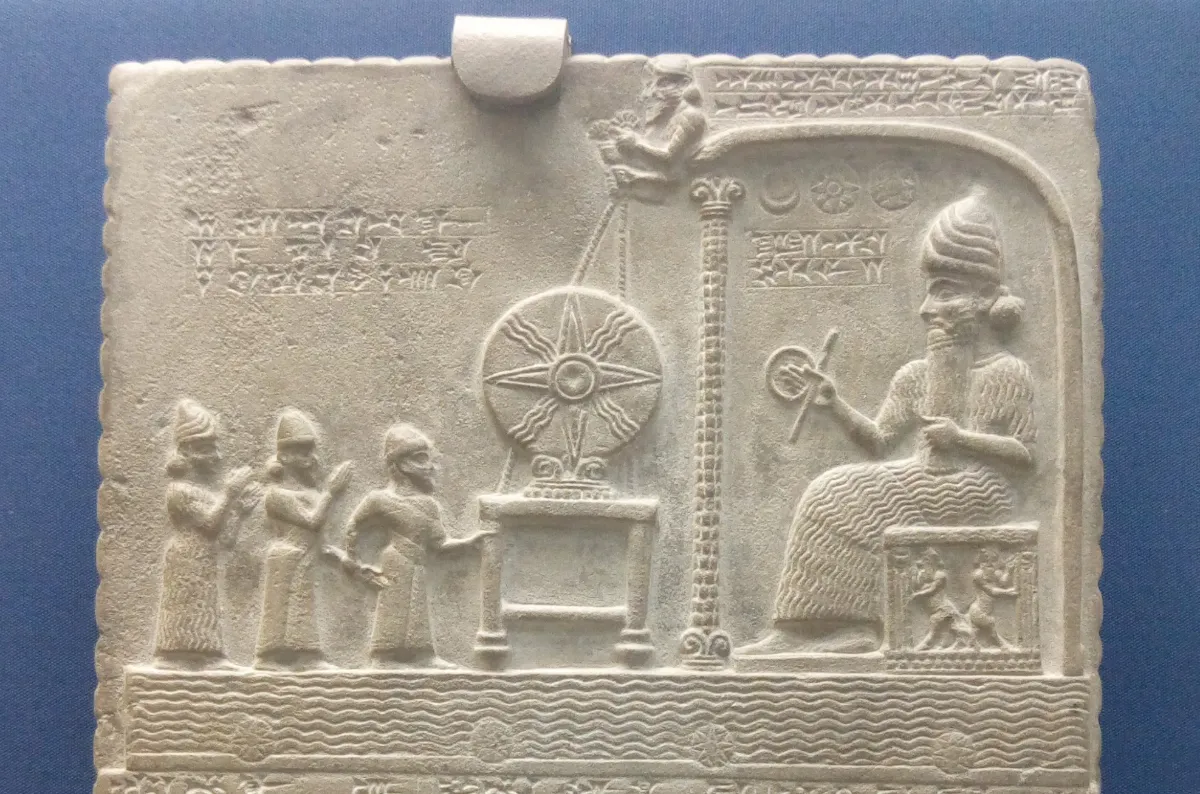 The top of a carved limestone tablet: a seated god under a canopy faces a large disc on an altar, the disc marked with a four-armed star and wavy rays between the arms.