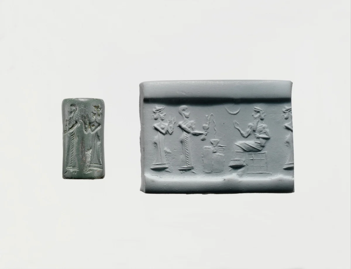 A small green stone cylinder seal beside its rolling: a worshipper and a standing figure before a seated god, with a crescent in the field.