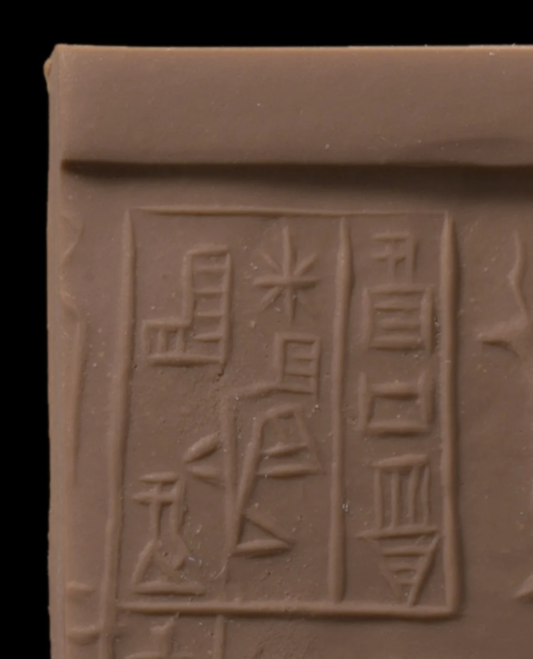 Close view of the box of cuneiform on the clay rolling; at the top of the middle column, a star of eight crossing strokes.