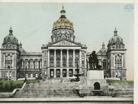Postcard of the stone Capitol from the front: a columned portico, a gold central dome, four smaller domes at the corners, broad steps and a bronze statue group.
