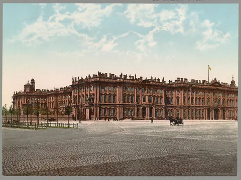 Colour photochrom of a long three-storey baroque palace with rooftop statues, seen across a wide cobbled square, with a horse-drawn carriage in the foreground.